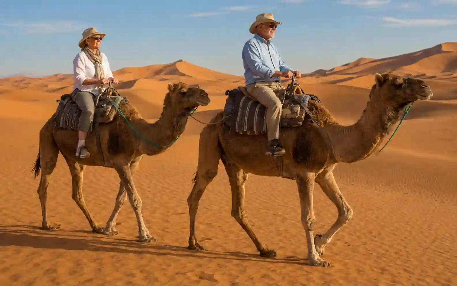 Senior couple riding camels in the Sahara on a Marrakech to Merzouga tour
